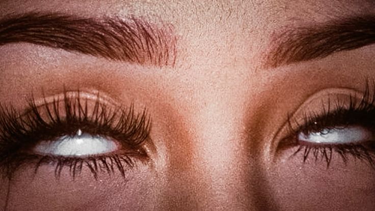 Extreme close-up of rolled-back eyes and long lashes after climax.